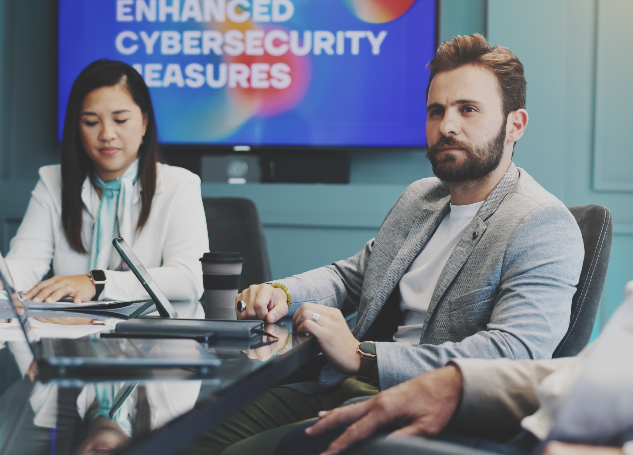 Woman and man around a conference table listening to a speaker.