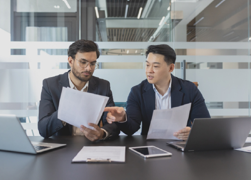 Two employees in a conference room collaborating and looking at data.
