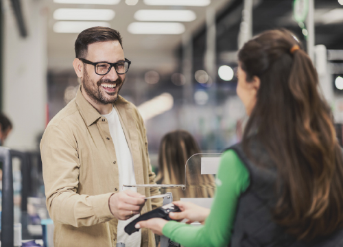 A man talking to a retail employee and using a credit card reader.