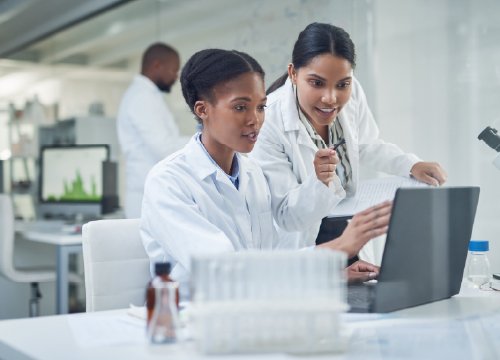 Life sciences workers collaborating at a work station looking at Exostar's platform life sciences