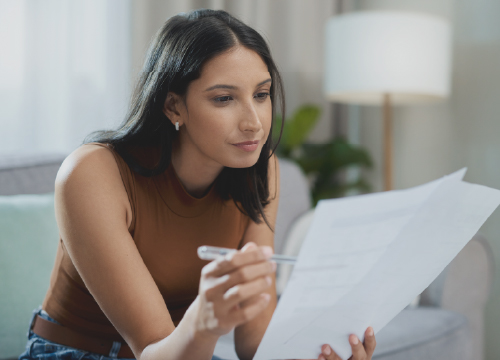 Young woman reading papers containing policies for CMMC.