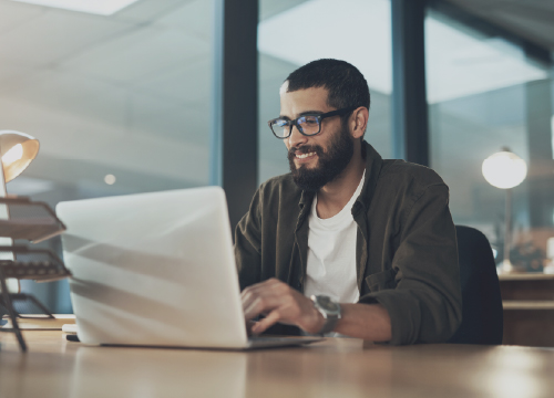 Man in glasses sitting at a table looking at his laptop for secure email.